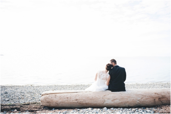 Bride and groom wedding portraits on the beach in Bellingham sitting on a driftwood looking out into the ocean