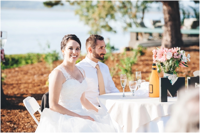 Bride and groom sitting at the head table at a backyard beach wedding in Bellingham as they listed to speeches