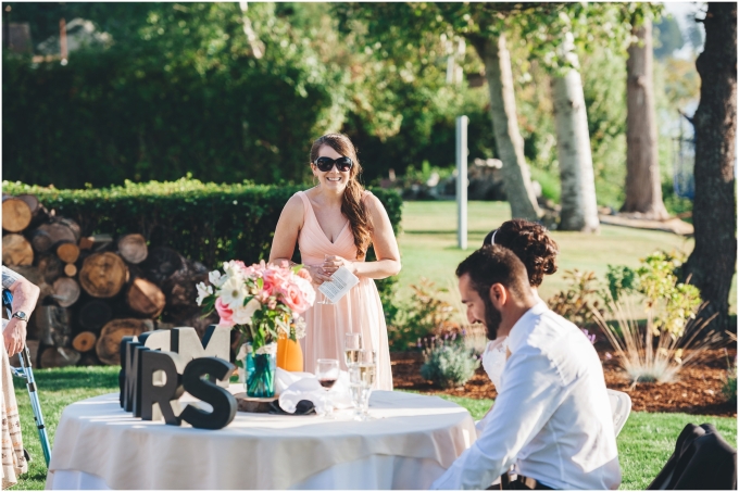 Maid of honor giving her speech at a backyard beach wedding while the bride and groom look at her