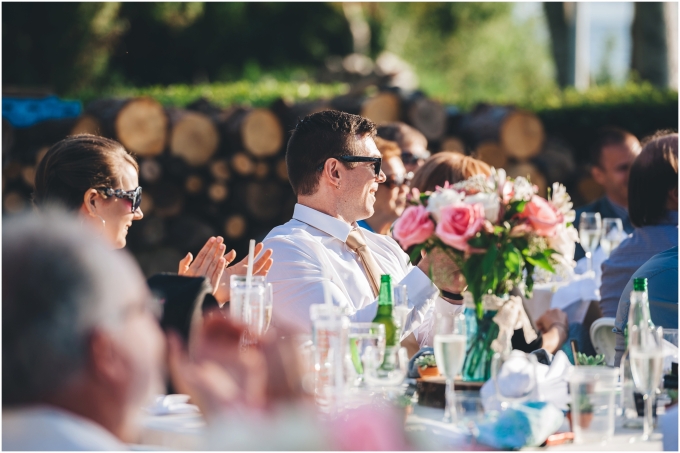 Guests sitting at the tables and laughing and enjoying a backyard wedding on a beach in Bellingham