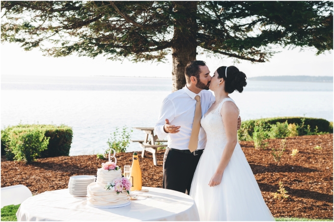 Bride and groom kissing after cutting their wedding cake at a backyard wedding on a beach in Bellingham